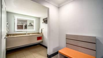 A modern bathroom with a vanity, mirror, and bench.