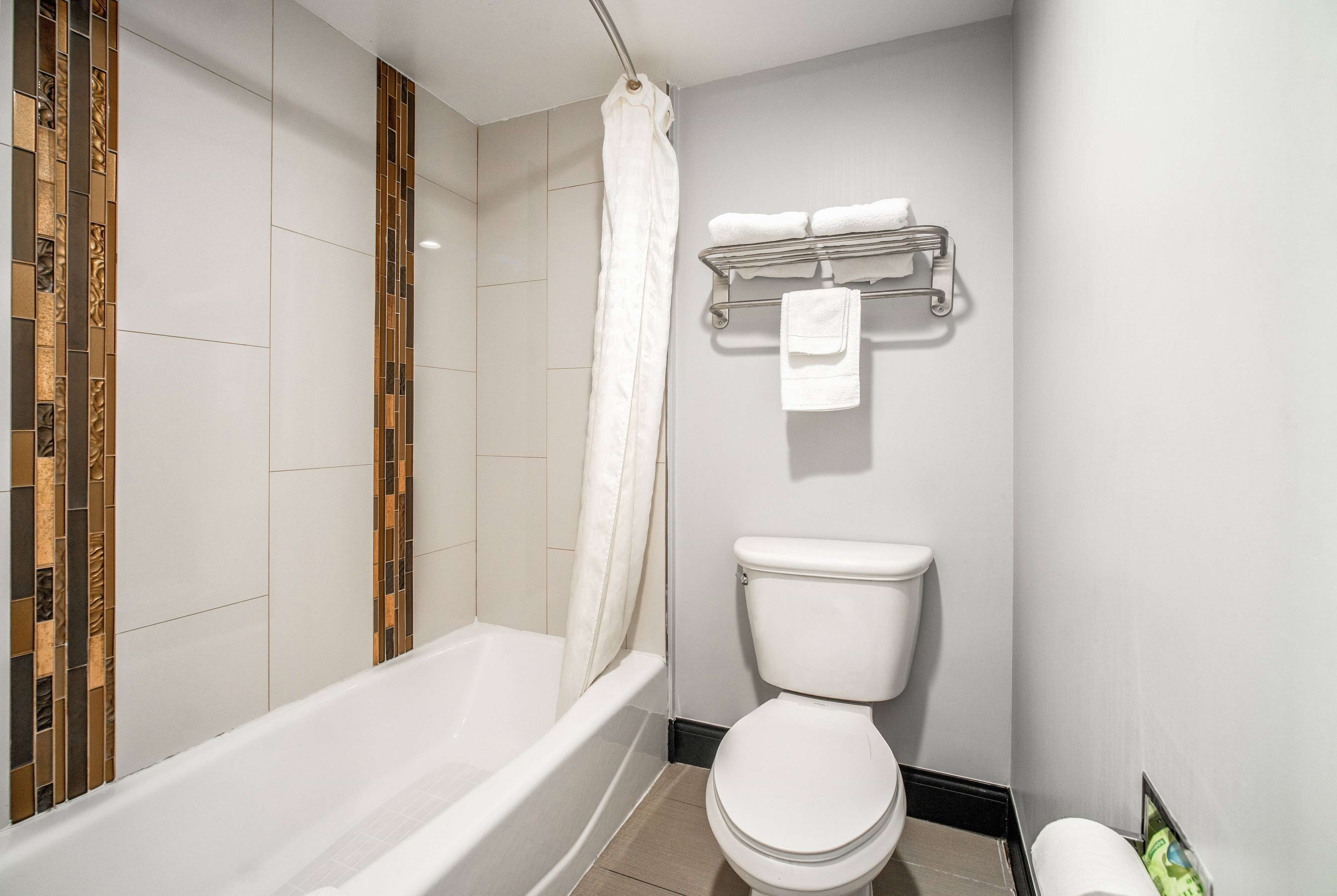 A bathroom with a bathtub, toilet, and a towel rack with towels.