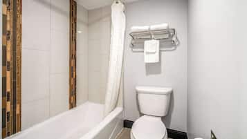 A bathroom with a bathtub, toilet, and a towel rack with towels.