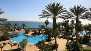 A resort with a large pool, palm trees, and a view of the ocean. - R2 Pájara Beach Hotel & Spa - All Inclusive (Pajara)