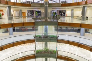 Un atrium de diversos nivells amb una font central, baranes de vidre i un paviment de rajoles.