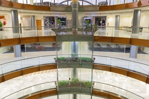 A multi-level atrium with a central water feature, glass railings, and a tiled floor.