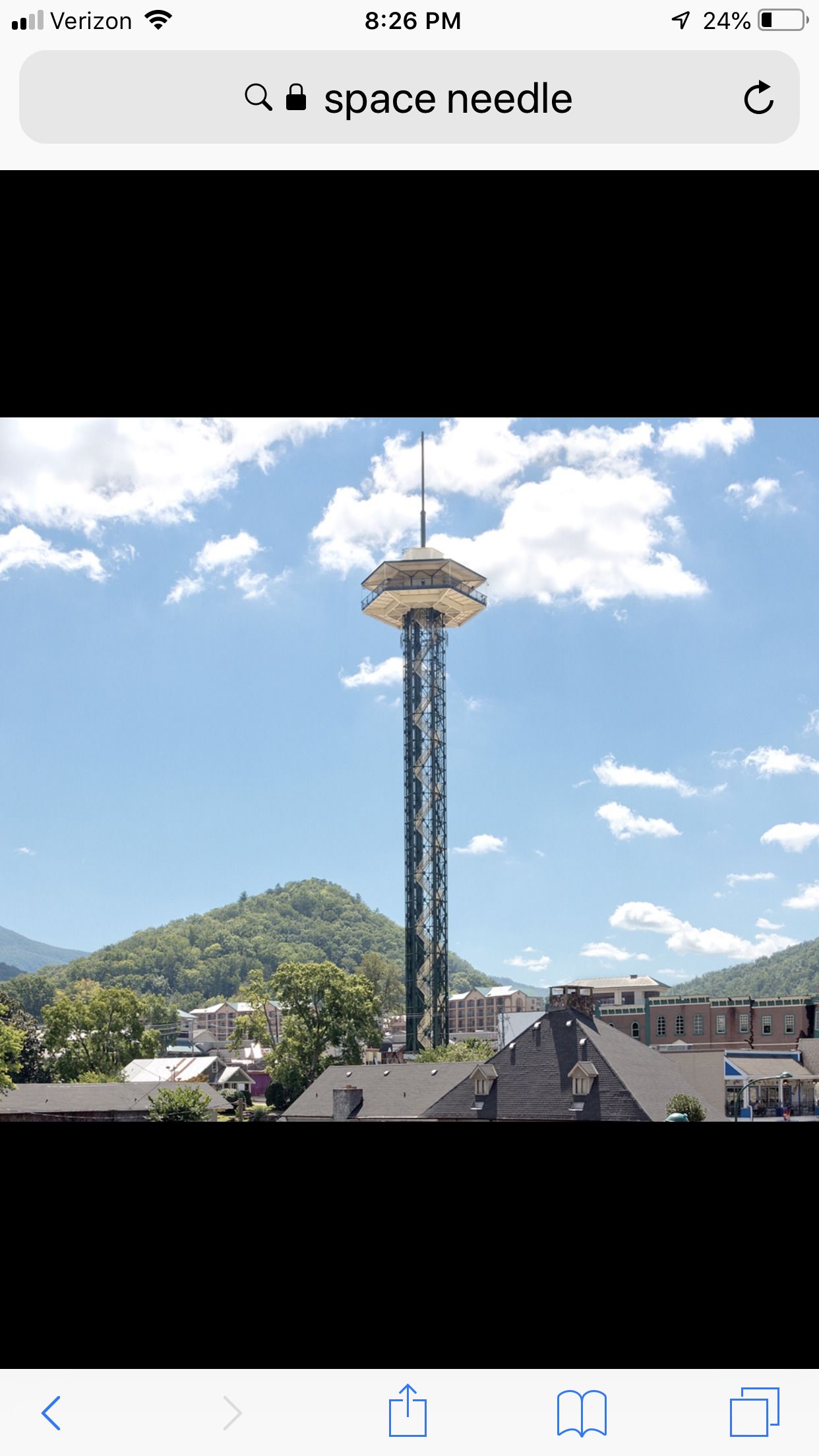 A tall tower with a circular observation deck, surrounded by buildings and greenery.