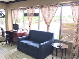 A room with a blue sofa, a desk with a computer, and a window with patterned curtains.