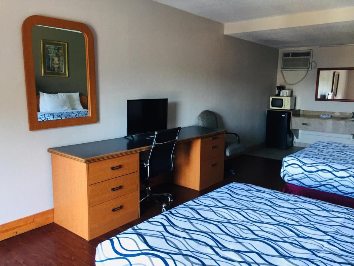 Une chambre d’hôtel équipée d’un lit, d’un bureau avec des tiroirs, d’une chaise, d’une télévision et d’un four à micro-ondes.