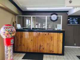 A reception desk with a clock, a gumball machine, and a television screen.
