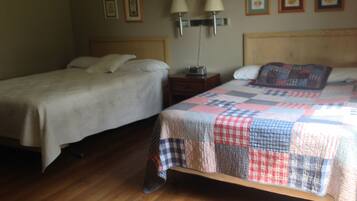 Un dormitorio con dos camas, suelo de madera, lámparas de noche y cuadros en la pared.