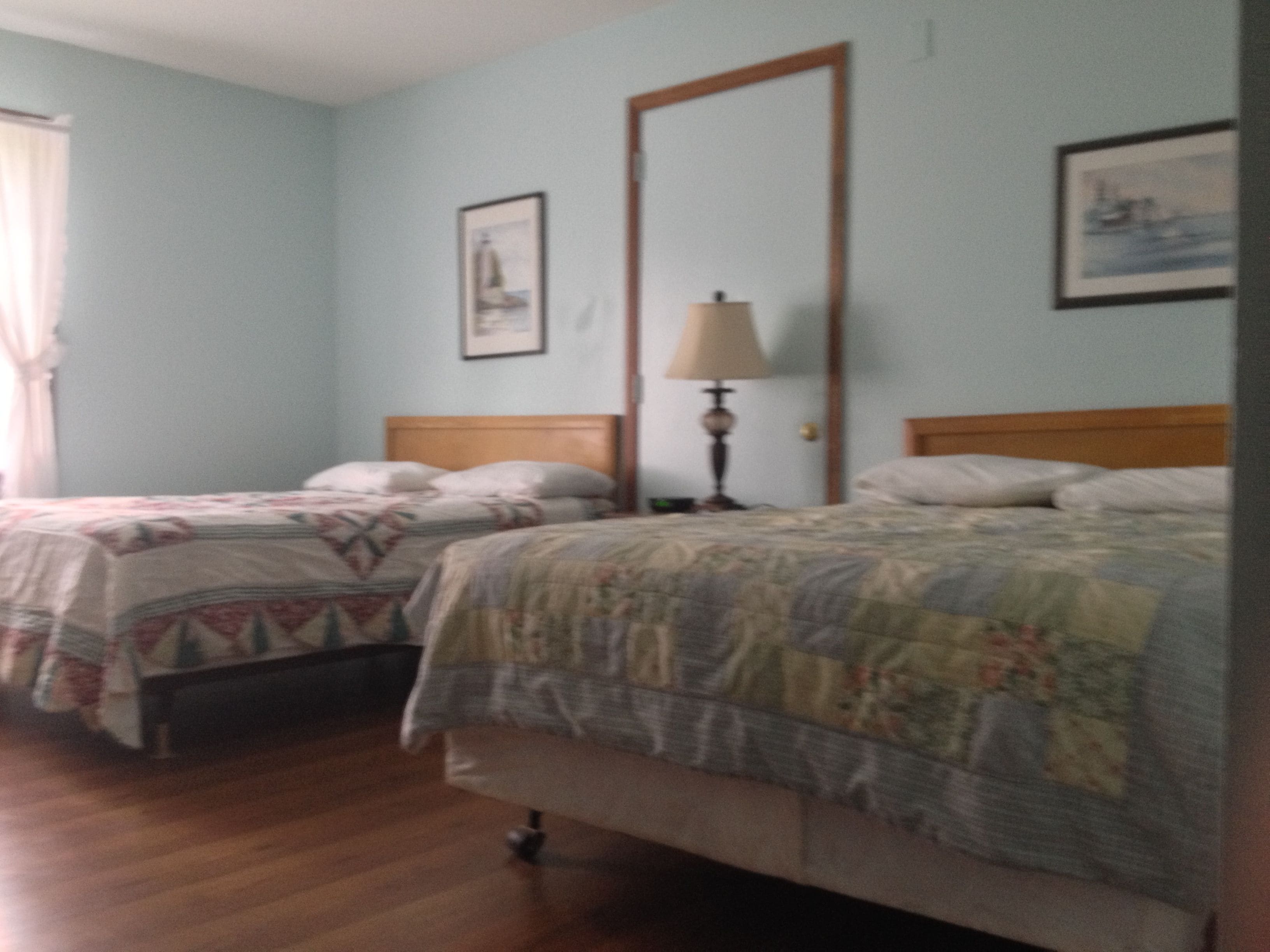 A bedroom with two single beds, a nightstand with a lamp, and a framed picture on the wall.