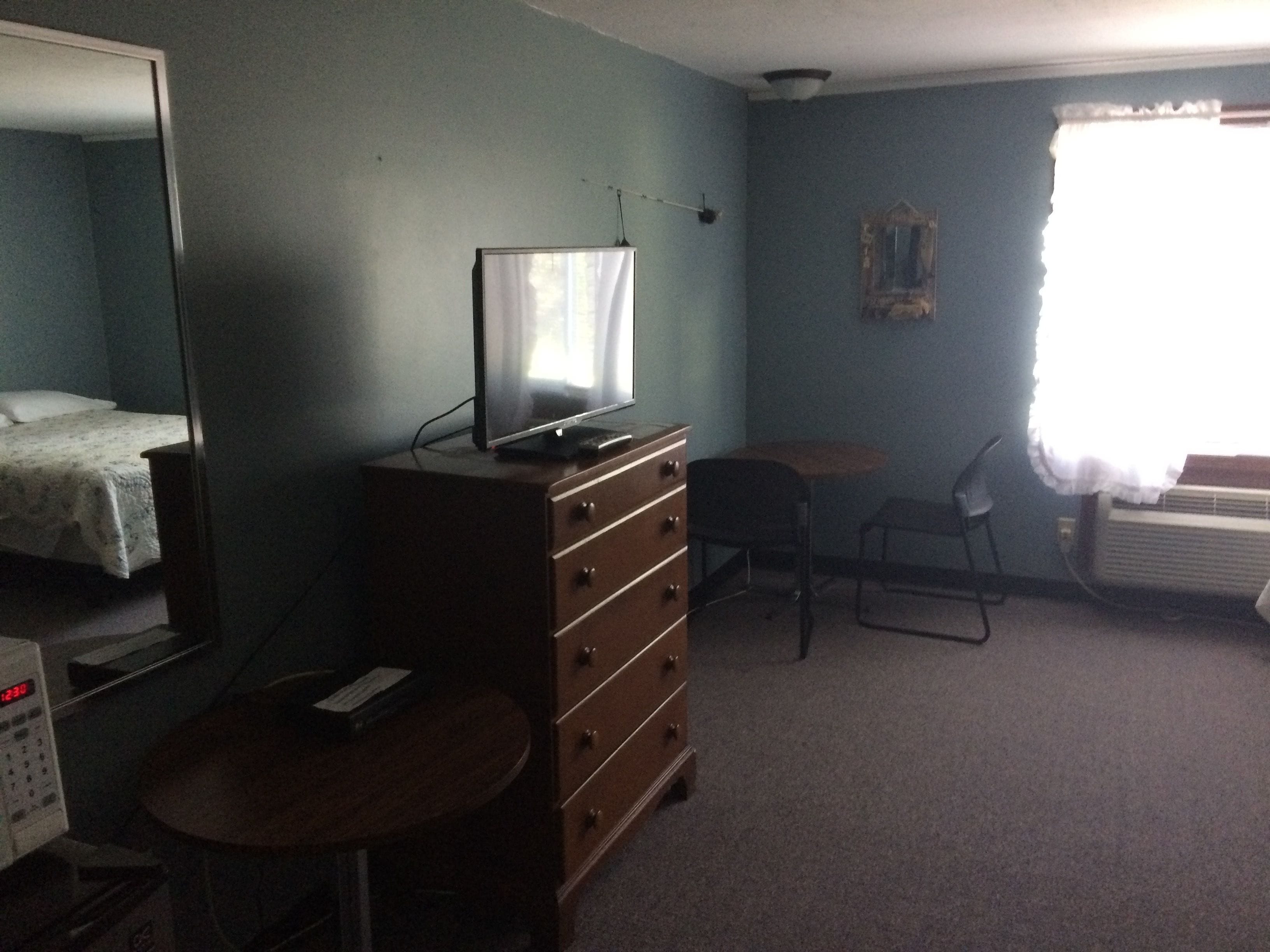 A room with a bed, a dresser, a desk, a chair, and a radiator.