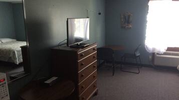 A room with a bed, a dresser, a desk, a chair, and a radiator.