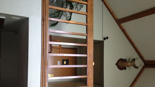 A wooden staircase with a view of a room below, a mounted deer head, and a door with a lock. - Chaffee Lodge (Chaffee)