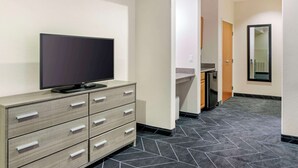 A hotel room with a flat-screen TV on a wooden dresser, a small kitchenette, and a tiled floor. - Best Western Lubbock West Inn & Suites (Lubbock)