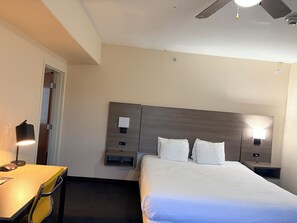 A hotel room with a bed, bedside tables, a desk, and a chair. - Lubbock West Inn & Suites (Lubbock)