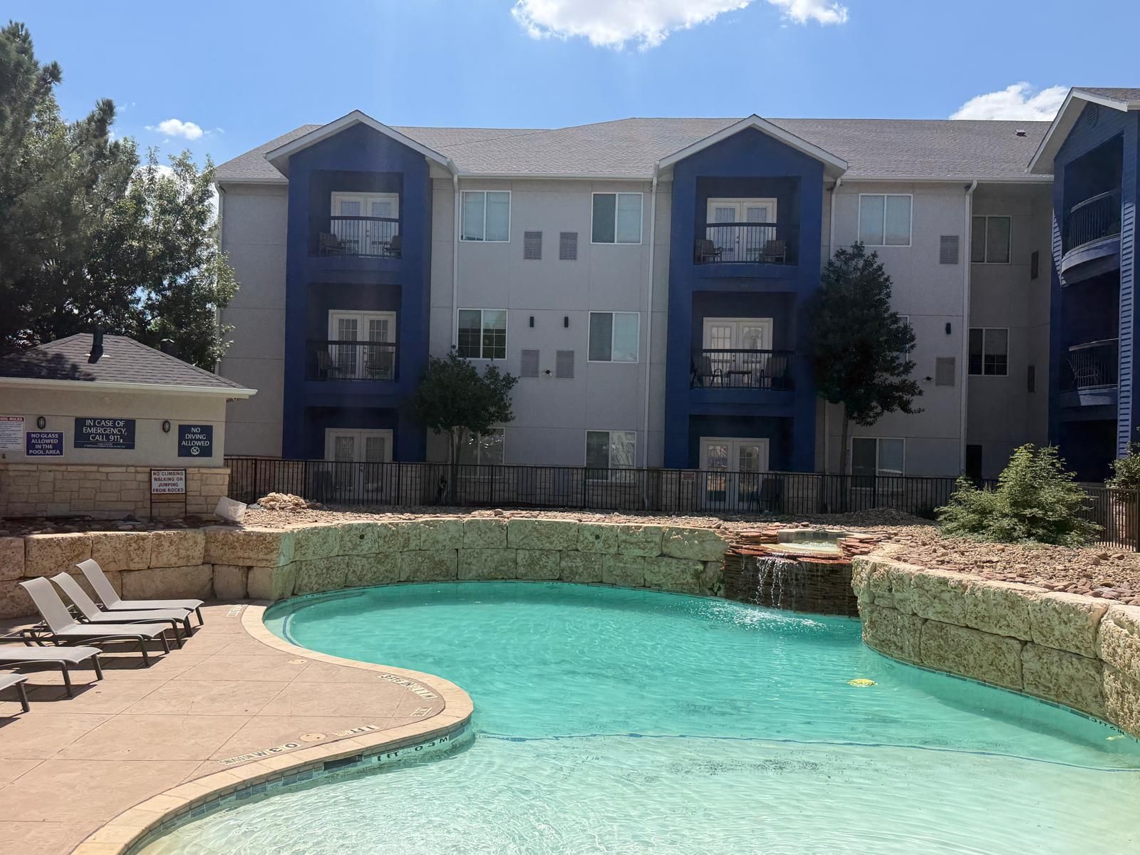 Un edificio residencial con piscina, varios balcones y zona vallada.