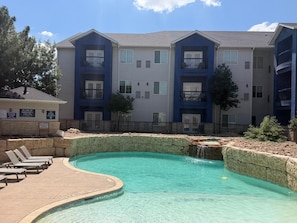 A residential building with a swimming pool, multiple balconies, and a fenced area. - Lubbock West Inn & Suites (Lubbock)