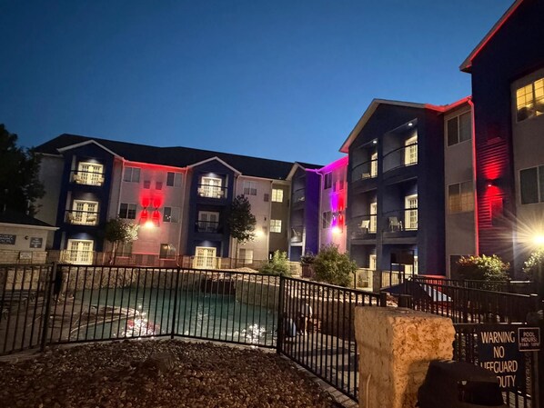 A multi-story building with balconies, a swimming pool, and a warning sign indicating no lifeguard duty. - Lubbock West Inn & Suites (Lubbock)