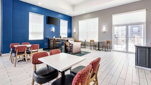 Un comedor moderno con paredes azules, mesas blancas y sillas rojas con estampado.