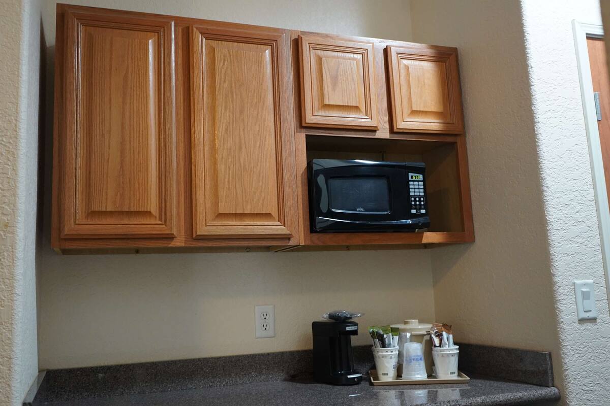 A kitchen with wooden cabinets, a microwave, and a coffee maker on the counter.