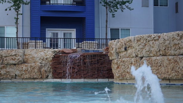 Una piscina con cascada y pared de piedra.
