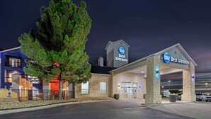 Un hotel Best Western con fachada de piedra, un gran árbol en frente y un estacionamiento.