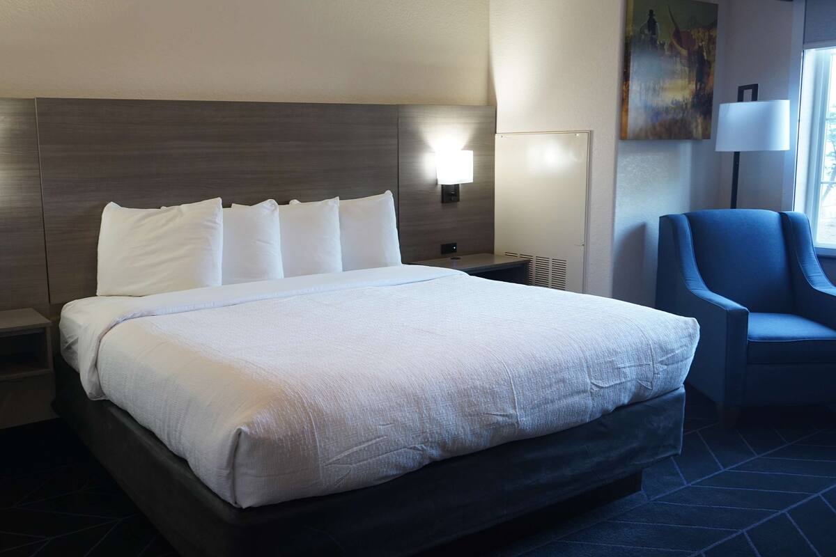 A neatly made bed with white linens, a dark headboard, and two wall-mounted lamps.