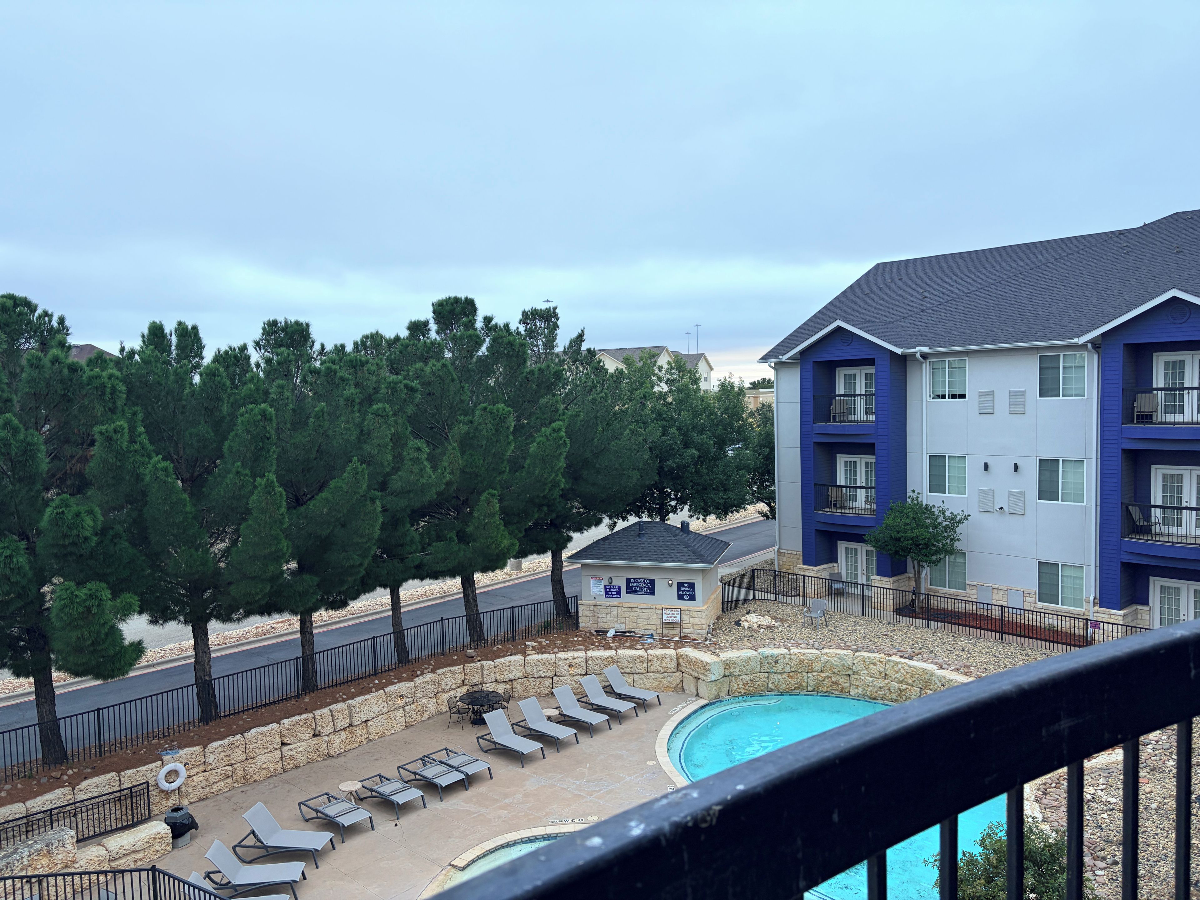 Un immeuble résidentiel doté d’une piscine, de chaises longues et d’un mur de soutènement en pierre.
