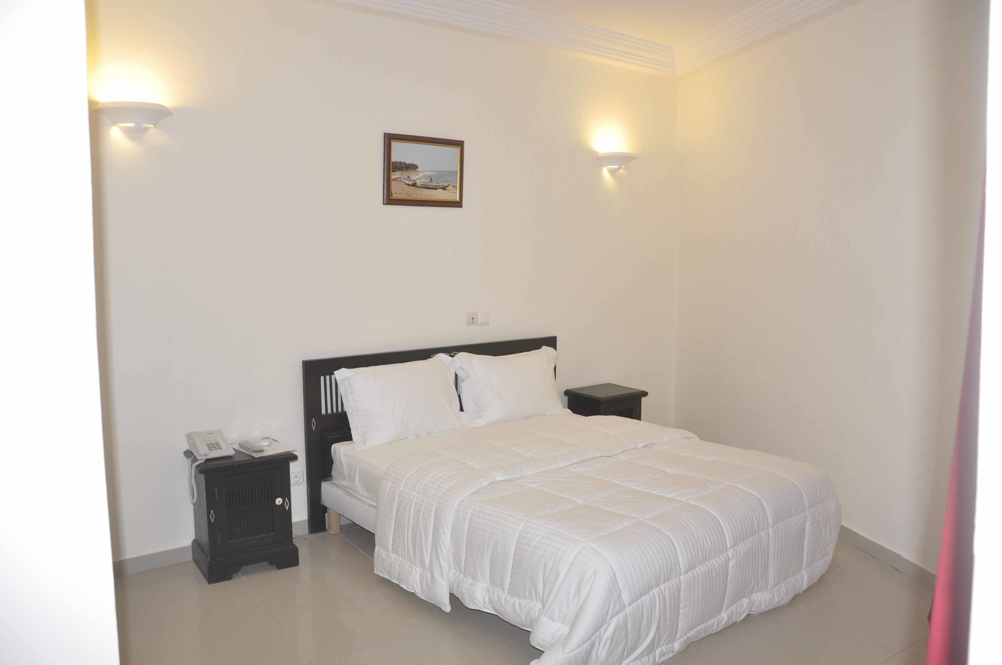 Un dormitorio con una cama, mesitas de noche y un cuadro colgado en la pared.