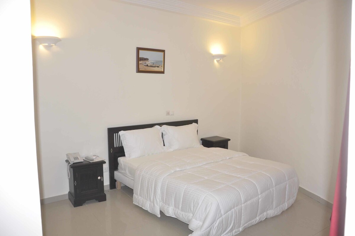 A bedroom with a bed, bedside tables, and a wall-mounted picture.