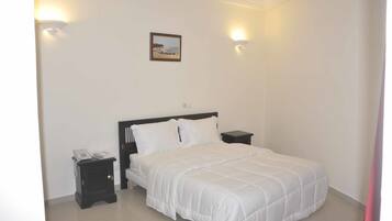 Un dormitorio con una cama, mesitas de noche y un cuadro colgado en la pared.