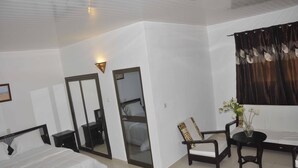 Habitación de hotel con cama, escritorio, silla, mesita, espejo y ventana con cortinas.