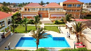 Un hotel con piscina, palmeras y techo de tejas rojas.
