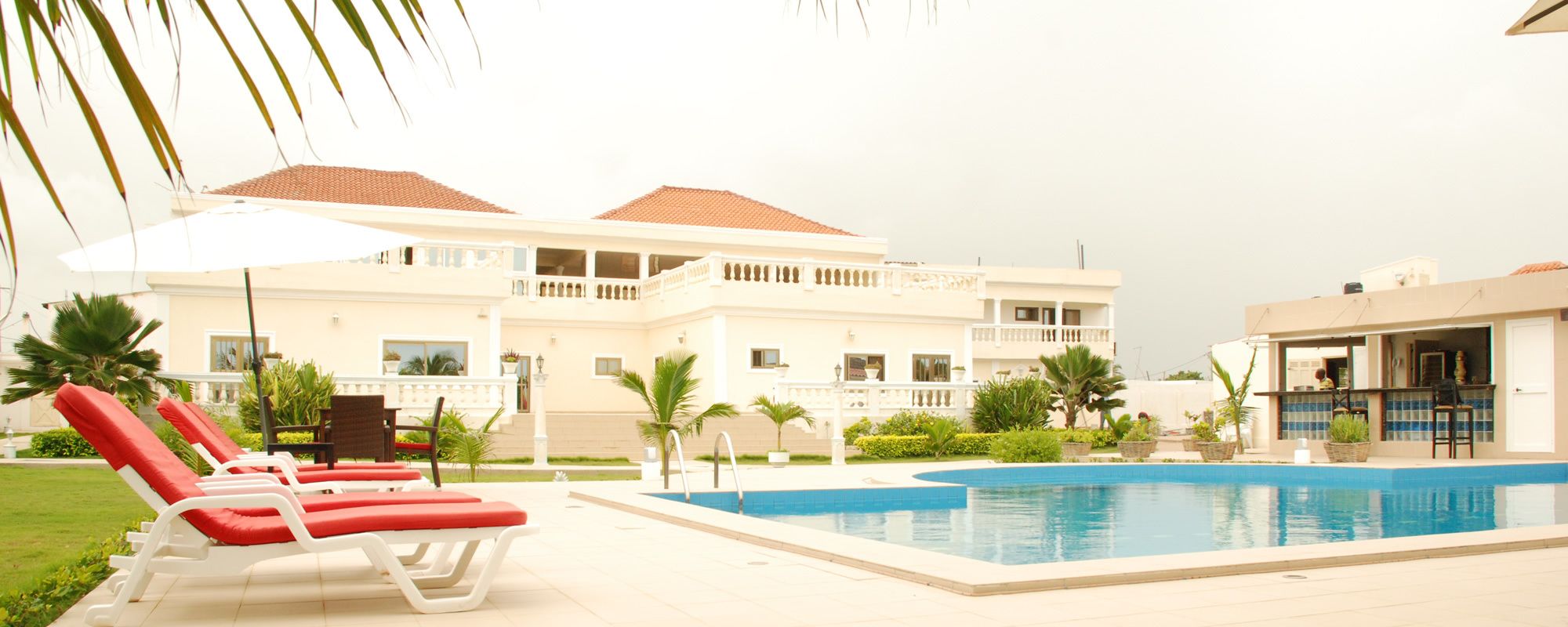 A pool area with lounge chairs and a building with balconies.