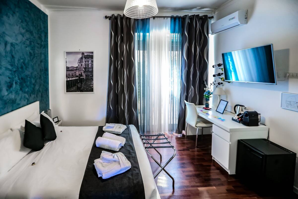 A hotel room with a bed, desk, and a TV.