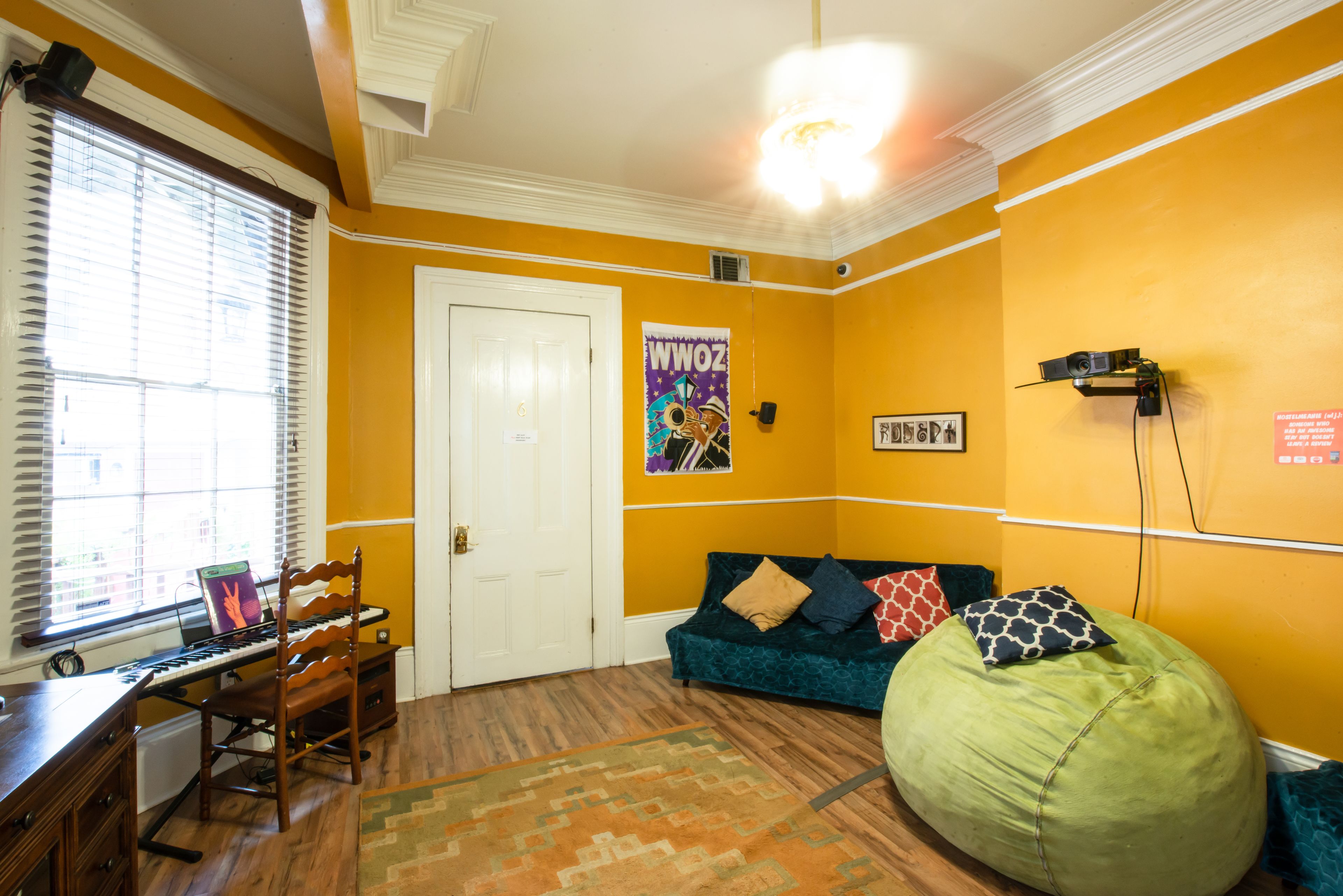 A room with a wooden desk, a green bean bag, a teal sofa, and a poster on the wall.
