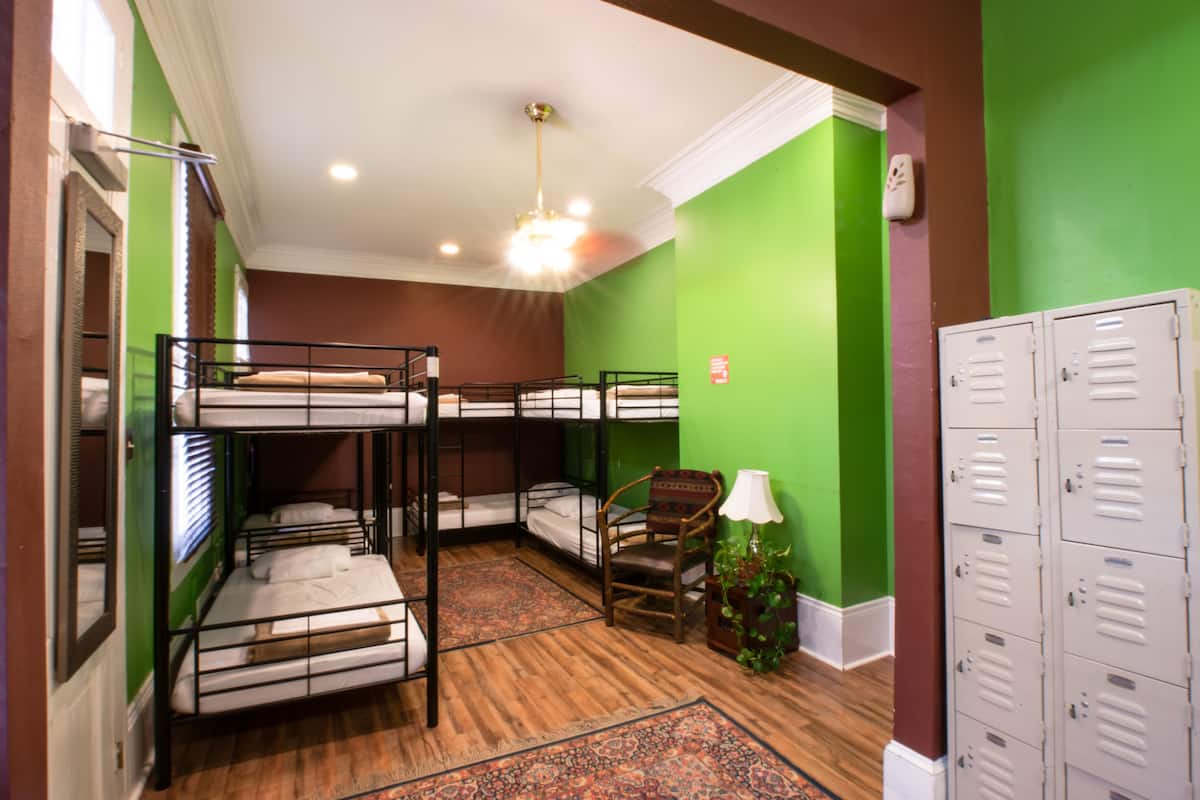 A room with bunk beds, a chair, a lamp, and a set of lockers.