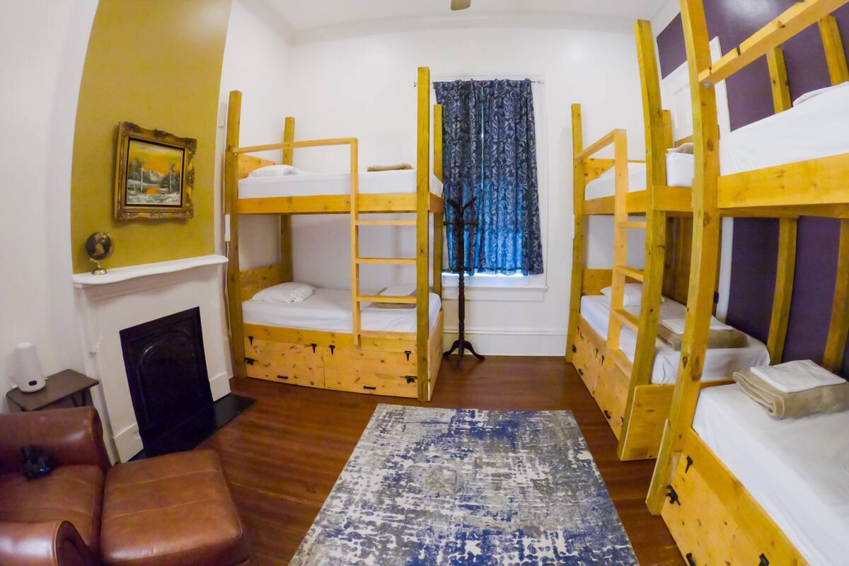 A room with bunk beds, a fireplace, a standing lamp, and a window with curtains.