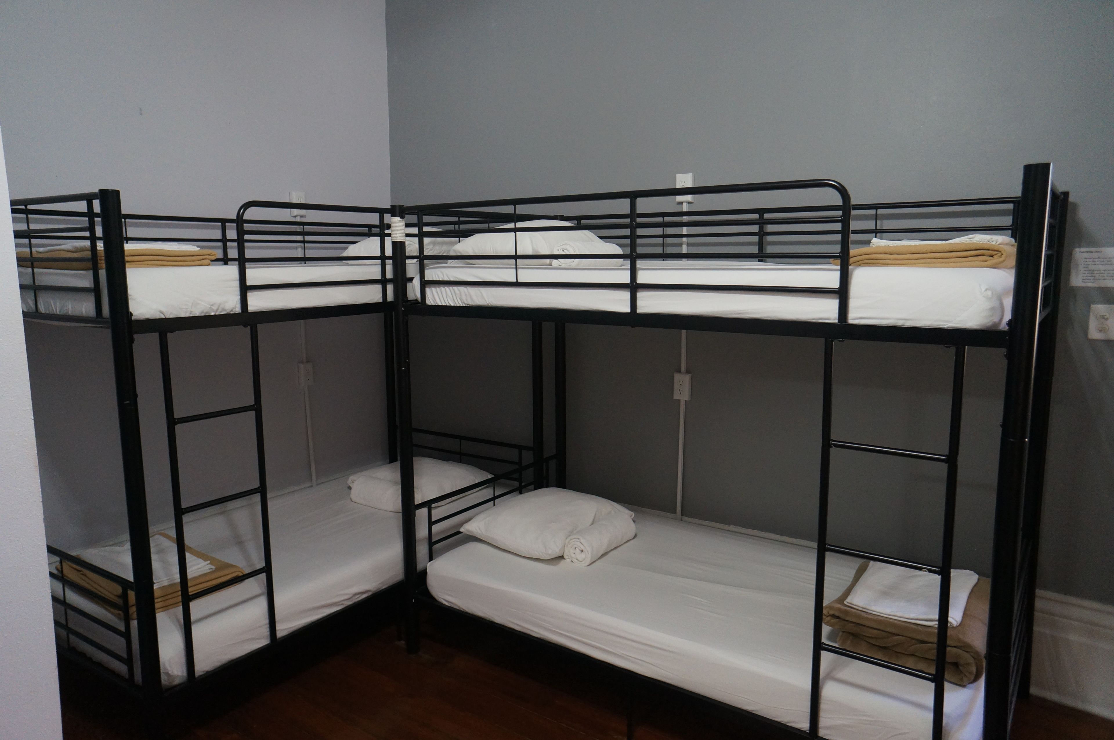 Dormitorio con literas, dos camas con estructura de madera y ropa de cama blanca.