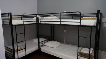 Dormitorio con literas, dos camas con estructura de madera y ropa de cama blanca.