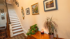 Una escalera con barandilla, un tapete estampado y una mesa de madera con una vela y una planta en maceta.