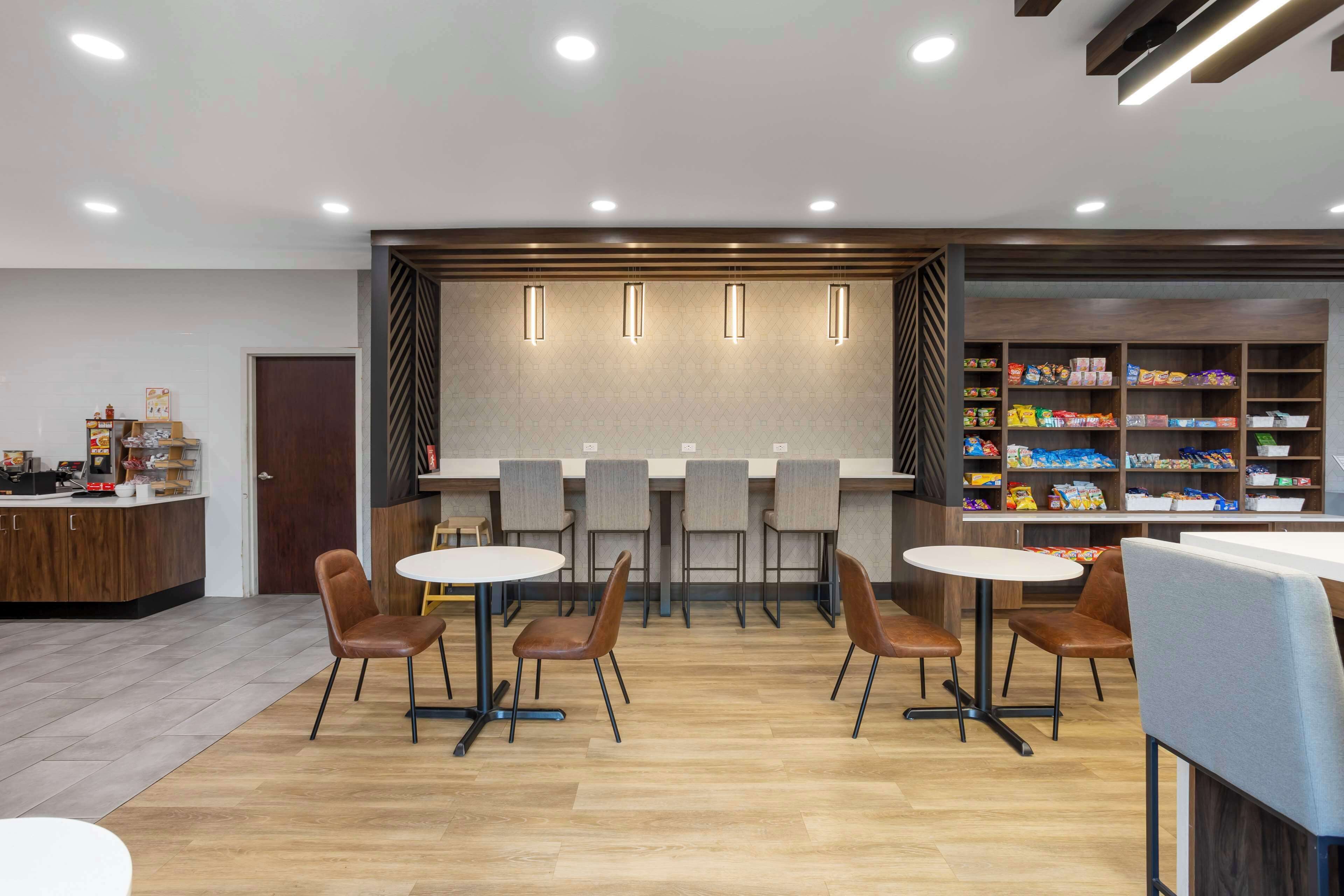 Un café moderne avec un plancher en bois, un bar doté de tabourets et des étagères remplies d’en-cas.
