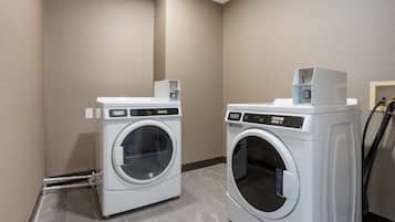 Two front-loading washing machines in a laundry room with beige walls and tiled flooring.