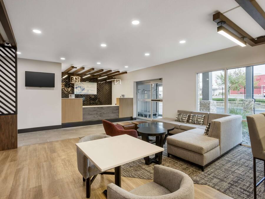 Un hall d’entrée moderne avec un canapé, des fauteuils, une table, un téléviseur et un comptoir d’accueil.