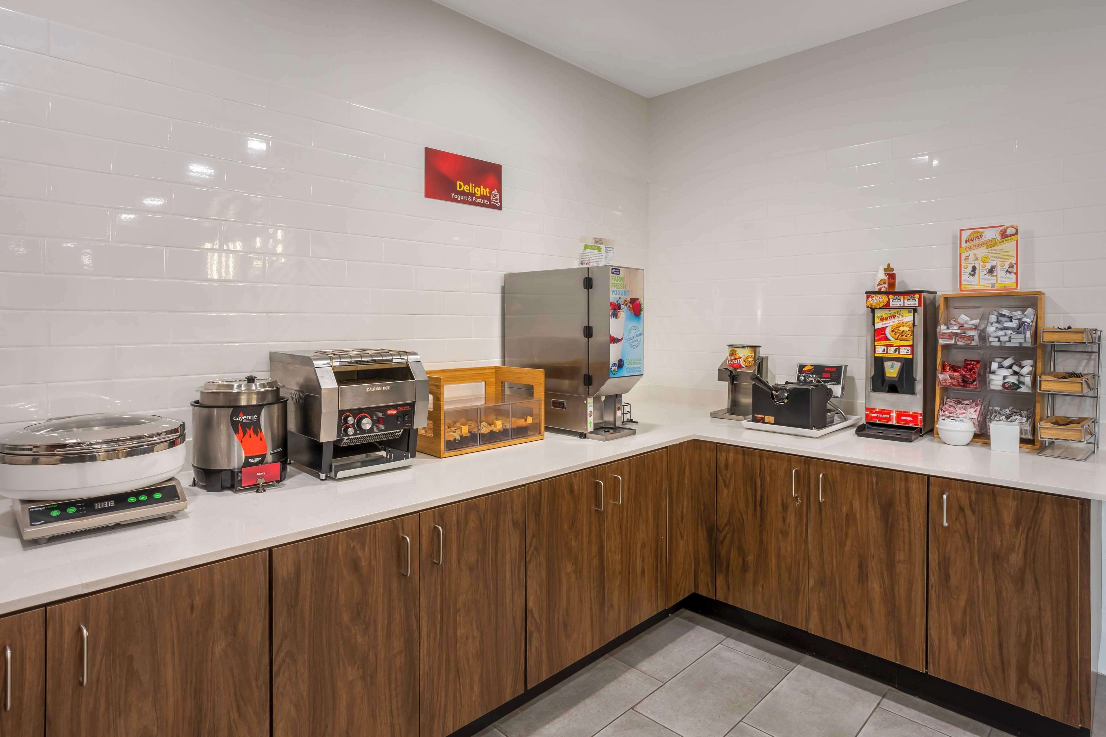 Een moderne keuken met een koffieapparaat, een broodrooster, een rijstkoker en een koelkast.