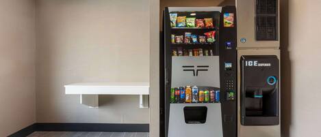 A vending machine with snacks and a water dispenser in a hotel room.