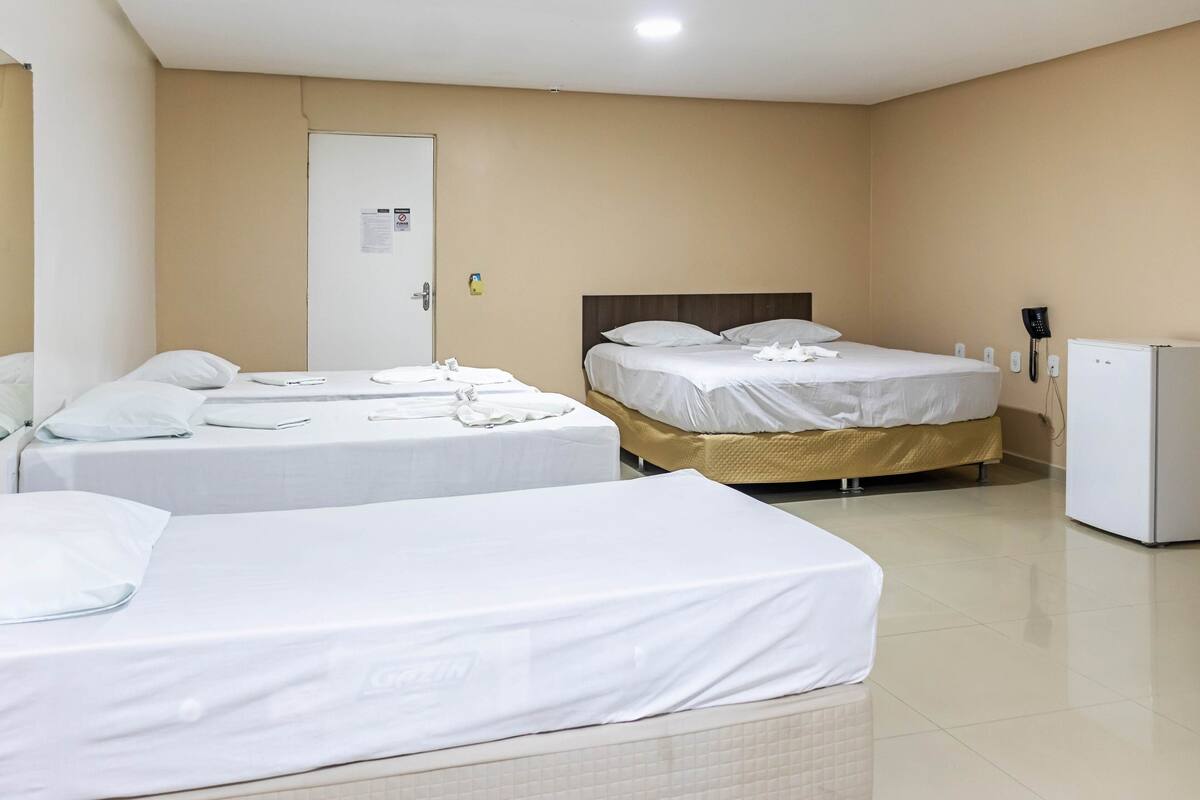Une chambre d’hôtel avec deux lits, une porte, un téléphone fixé au mur et un petit réfrigérateur.
