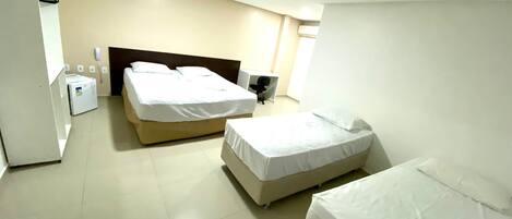 Habitación de hotel con dos camas, un escritorio, una silla, un armario y una mesita de noche.