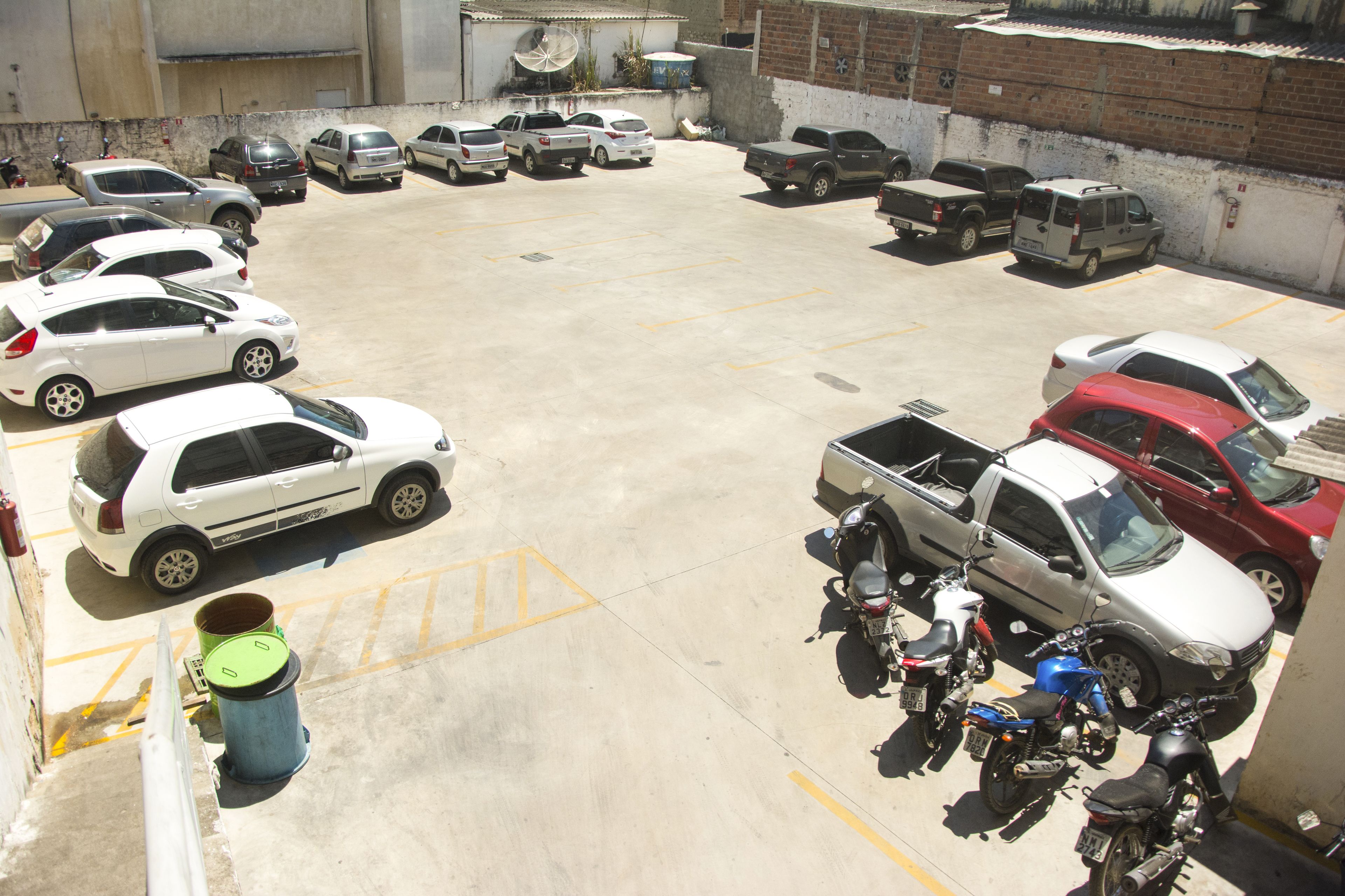 Un estacionamiento con diversos vehículos, incluyendo automóviles y motocicletas.