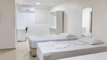 A hotel room with two beds, white bedding, a large mirror, and a phone on the wall.