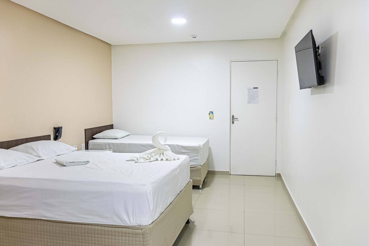 Une chambre d’hôtel avec deux lits, un téléviseur fixé au mur et une porte sur laquelle est apposé un avis.