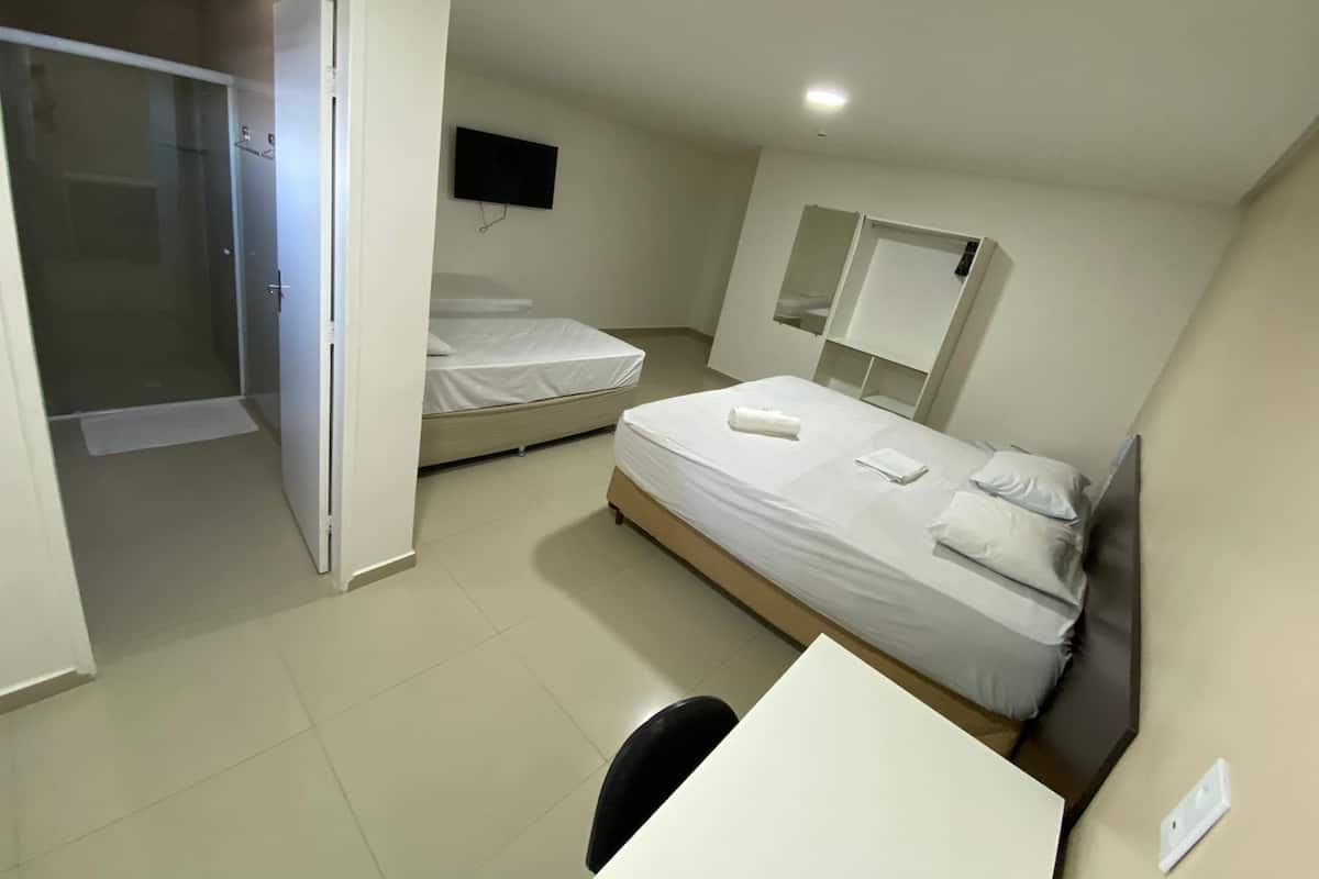 Une chambre d’hôtel avec deux lits, un bureau, une télévision et un espace douche.